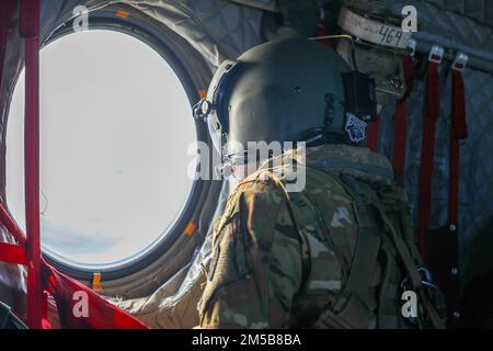 USA Army Sergeant Najja Robinson, ein CH-47-Helikopter-Reparateur bei Bravo Company, 3. Bataillon, 25. Luftfahrtregiment, 25. Kampfluftfahrtbrigade, blickt aus dem Fenster einer Boeing CH-47F, nachdem sie vom 18. Februar 2022 in Oahu, Hawaii, gestartet war. Die Crew nahm an der Qualifizierungsschulung für Deckslandungen neben den USA Teil Marine an Bord der USS Portland (LPD 27), um die Fähigkeit zur Unterstützung von maritimen Missionen in der Region Indo-Pazifik aufrechtzuerhalten. Stockfoto