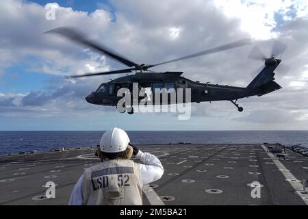 PACIFIC OCEAN (18. Februar 2022) Chief Boatswain's Mate Kelly Pfaus, ein aus San Francisco stammender Angehöriger der Army UH-60 Blackhawk, der einem CO 2-25. Aviation Regiment angeschlossen ist, während es vom Flugdeck des Amphibiendock-Landungsschiffs der Harpers Ferry-Klasse USS Pearl Harbor (LSD 52) startet; Im Pazifischen Ozean, 18. Februar 2022. Matrosen und Marines der Essex Amphibious Ready Group (ARG) und der 11. Marine Expeditionary Unit (MEU) führen derzeit Routineeinsätze in der US-amerikanischen 3.-Flotte durch. Stockfoto