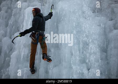 Fernando Martinez, ein Reiseleiter des Outdoor Recreation Center, skaliert die Seite eines Eisbergs während einer Klettertour mit dem „Better Opportunities for Single Soldiers“-Programm und dem Outdoor Recreation Center, Directorate of Family and Morale, Welfare and Recreation“, 18.-19. Februar 2022 in Ouray, Colorado. Martinez sagte, er arbeite gern mit Menschen zusammen und unterrichtet sie über neue Aktivitäten. Stockfoto