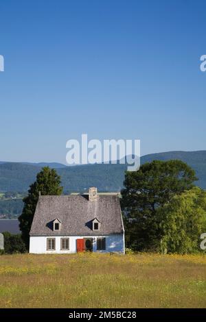 Altes französisches Regime Weiße Holzplanke aus den 1752 Jahren mit Zedernschindeln Dach Cottage-Haus im Sommer, Saint-Francois, Ile d'Orleans, Quebec, Kanada. Stockfoto