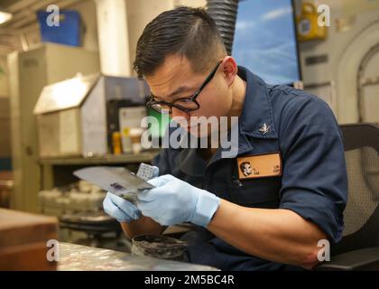 PHILIPPINE SEA (19. Februar 2022) Aviation Structural Mechanic 3. Class Yangliu Lin aus Flagstaff, Arizona, verschleiert ein Panel an Bord des Flugzeugträgers der Nimitz-Klasse USS Abraham Lincoln (CVN 72). Die Abraham Lincoln Strike Group befindet sich in einem geplanten Einsatz im US-7.-Flottenbereich, um die Interoperabilität durch Allianzen und Partnerschaften zu verbessern und gleichzeitig als einsatzbereite Truppe zur Unterstützung einer freien und offenen Region Indo-Pacific zu fungieren. Stockfoto