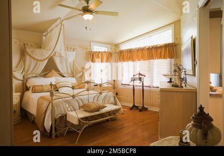 Antikes Queen-size Himmelbett mit schmiedeeisernem Kopfteil und Fußbrett im Hauptschlafzimmer im 1987. Archimed Stil Haus. Stockfoto