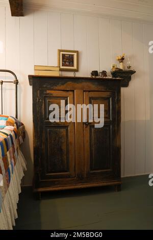 Antike Schränke neben dem Doppelbett mit Patchwork-Steppdecke im Hauptschlafzimmer im Obergeschoss in einem alten Haus im französischen Stil von 1772. Stockfoto