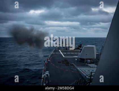 Der Zerstörer der Führungsraketen USS Delbert D. Black (DDG 119) feuert seine MK-45 5-Zoll-Pistole während einer SWATT-Übung (Surface Warfare Advanced Tactical Training) ab. Delbert D. Black ist Teil der Destroyer Squadron (DESRON) 26, die die Carrier Strike Group (CSG) 10 unterstützt. SWATT wird vom Naval Surface and Mine Warfighting Development Center (SMWDC) geleitet und soll die Kampffähigkeit, die Letalität und die Interoperabilität oder die teilnehmenden Einheiten verbessern. Stockfoto