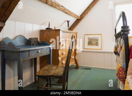 Blauer, antiker Holzschreibtisch und Stuhl mit hoher Rückenlehne und Kommode im Hauptschlafzimmer im oberen Stockwerk im alten Haus im französischen Stil von 1722. Stockfoto