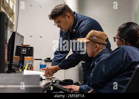 220221-N-XB010-1001 EAST CHINA SEA (21. Februar 2022) Personnel Specialist 2. Class Sammy Rivera, from New Castle, Del., Left, bietet eine hochwertige Schulung für den Personnel Specialist 3. Class Angelo Pangilinan, aus Union City, Kalifornien, Center, an Bord der USS New Orleans (LPD 18). New Orleans, Teil der America Amphibious Ready Group, ist zusammen mit der 31. Marine Expeditionary Unit im Zuständigkeitsbereich der US-amerikanischen 7.-Flotte tätig, um die Interoperabilität mit Verbündeten und Partnern zu verbessern und als einsatzbereite Eingreiftruppe zur Verteidigung von Frieden und Stabilität in der Region Indo-Pazifik zu dienen. Stockfoto