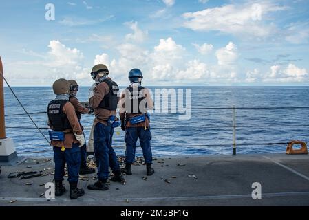 USA Besatzungsmitglieder der Küstenwache, die der USCGC Stratton (WMSL 752) zugeteilt sind, bereiten sich darauf vor, während einer Schießübung an Bord des Schneiders im Pazifik am 22. Februar 2022 ein Maschinengewehr Kaliber .50 abzufeuern. Die Besatzung von Stratton hält die Fähigkeiten aufrecht und erweitert sie, um eine kompetente Besatzung während des Fluges in der Pazifikregion zu gewährleisten. Stockfoto