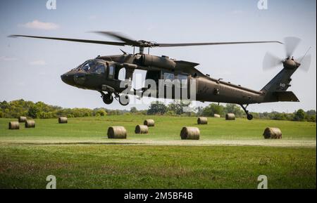 Ein Feld von Heuballen umrahmt eine Iowa Army National Guard UH-60 Black Hawk, während es einen Anhänger während eines U.S. Pathfinder Kurses im Camp Dodge in Johnston, Iowa, am 8. September 2022 belädt. Fast 30 Soldaten absolvierten den Kurs, der von einem mobilen Trainingsteam im Warrior Training Center der Army National Guard in Fort Benning, Georgia, unterrichtet wurde. Army Pathfinders werden geschult, um Navigationshilfe und Beratungsdienste für Militärflugzeuge in Gebieten zu leisten, die von unterstützten Einheiten-Kommandeuren bestimmt werden. Während des Pathfinder-Kurses werden die Studenten in der Flugzeugorientierung, der aerodynamischen Evakuierung, c Stockfoto