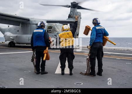 PHILIPPINE SEA (22. Februar 2022) Aviation Boatswain’s Mate (Handling) Airman Cassandra Flores, Center, aus Bakersfield, Kalifornien, zugewiesen an das nach vorn eingesetzte Amphibienschiff USS America (LHA 6), sendet Signale an ein Flugzeug des Typs MV-22B Osprey Tiltrotor von der Marine Expeditionary Unit (MEU) 31. auf dem Cockpit des Schiffes. Amerika, das führende Schiff der America Amphibious Ready Group, ist zusammen mit der 31. MEU im Zuständigkeitsbereich der US-amerikanischen 7.-Flotte tätig, um die Interoperabilität mit Verbündeten und Partnern zu verbessern und als einsatzbereite Eingreiftruppe zur Verteidigung von Frieden und Stabilität in den Indo-Paci zu dienen Stockfoto