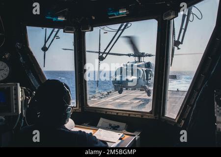 220222-N-GF955-1002 KARIBISCHES MEER - (21. Februar 2022) -- Boatswain’s Mate 1. Klasse Emmanuel Dixon zugeordnet zum Freiheitsvarianten-Küstenkampfschiff USS Billings (LCS 15) beobachtet vom Flugkontrollturm aus als MH-60s Sea Hawk Hubschrauber, der dem ‚Shadow Det‘ des Hubschraubers Sea Combat Squadron (HSC) 28, Einheit 7, startet vom Flugdeck, 21. Februar 2022. Billings wird in das US-Flottengebiet 4. entsandt, um die Mission der Joint Interagency Task Force South zu unterstützen, zu der auch Missionen zur Bekämpfung des illegalen Drogenhandels in der Karibik und im östlichen Pazifik gehören. Stockfoto