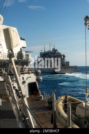 SÜDCHINESISCHES MEER (22. Februar 2022) der Arleigh-Burke-Class-Guided-Missile Destroyer USS Ralph Johnson (DDG 114) zieht neben dem Lewis- und Clark-Class-Trockenfrachtschiff USNS Carl Brashear (T-AKE-7) in Vorbereitung auf eine Wiederauffüllung auf See. Ralph Johnson ist der Task Force 71/Destroyer Squadron (DESRON) 15, dem größten nach vorn verlegten DESRON der Marine, und der Hauptstreitkraft der US-7.-Flotte zugewiesen. Stockfoto