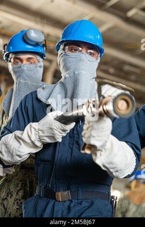 220222-N-NR343-2035 NEWPORT NEWS, VA (22. Februar 2022) – Aviation Boatswain’s Mate (Handling) Airman Jon Leonard A. Rodriguez Finister aus San Bernardino, Kalifornien, der der Abteilung Air an Bord des Flugzeugträgers der Nimitz-Klasse USS George Washington (CVN 73) zugewiesen wurde, demonstriert bei einer allgemeinen Quartierübung Techniken zur Handhabung von Schläuchen. George Washington wird bei Newport News Shipyard den Tankkomplex überholen (RCOH). RCOH ist ein mehrjähriges Projekt, das nur einmal während der 50-jährigen Lebensdauer eines Frachtführers durchgeführt wird und das Betanken der beiden Kernreaktoren des Schiffs sowie Signific umfasst Stockfoto