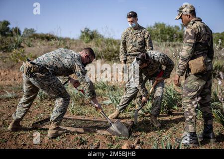 USA Marinetechniker für die Entsorgung von Sprengstoffen mit 2. Marine Logistics Group und Royal Moroccan Armed Forces (FAR) graben einen Graben, um während eines Sprengstoffabbruchbereiches in der Nähe von Khemisset, Marokko, am 23. Februar 2022 lebende Munition zu entsorgen. Marines, Matrosen und Mitglieder der Utah National Guard nehmen an der Humanitarian Mine Action, EOD Morocco 2022 Teil, wo die USA Die EOD-Techniker überwachen die EOD-Validierung der Soldaten der Royal Marokcan Armed Forces, um die Bemühungen zur Schaffung einer EOD-Fähigkeit innerhalb der FAR fortzusetzen. Stockfoto