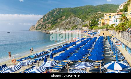 Kieselstrand Monterosso Urlaub Cinque Terre Monterosso Liegen und Sonnenschirme füllen den Strand Spiaggia di Fegina, Monterosso, Teil der Cinque Terre Italien. Stockfoto