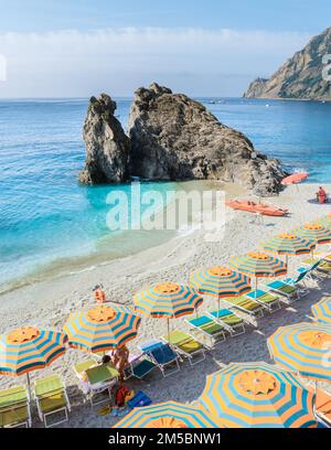 Kieselstrand Monterosso Urlaub Cinque Terre Monterosso Liegen und Sonnenschirme füllen den Strand Spiaggia di Fegina, Monterosso, Teil der Cinque Terre Italien. Stockfoto