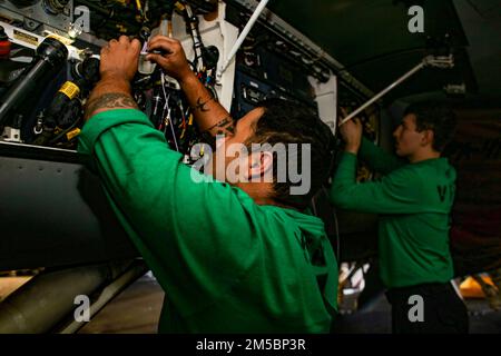 PHILIPPINE SEA (24. Februar 2022) Aviation Electronics Technician 1. Class Lara Donavan, Left, from Chandler, Ariz. Und Aviation Electricians Mate 2. Class Jared Richardson, aus Paradise, Texas, repariert Glasfaserkabel an einem F/A-18F Super Hornet, das dem „Black Aces“ des Strike Fighter Squadron (VFA) 41 zugewiesen wurde, in der Hangarbucht an Bord des Flugzeugträgers USS Abraham Lincoln (CVN 72) der Nimitz-Klasse. Die Abraham Lincoln Strike Group befindet sich im geplanten Einsatz im US-amerikanischen 7.-Flottenbereich, um die Interoperabilität durch Allianzen und Partnerschaften zu verbessern und gleichzeitig als einsatzbereite Lösung zu dienen Stockfoto