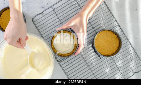 Kleines Käsekuchen-Rezept. Käsekuchen-Teig in eine vorbereitete Backform gießen, Nahzubereitung, flach legen Stockfoto