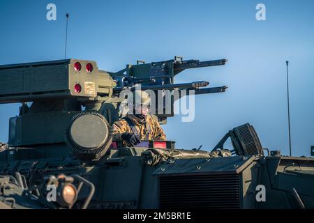 Ein US-Armeesoldat, der dem 5. Bataillon, dem 4. Air Defense Artillery Regiment, zugewiesen wurde, leitet den Fahrer seines Manövers „Short Range Air Defense Stryker“ vom ‘Tank Commander’ Luke während der Übung Sabre Strike 22 bei BPTA, Polen, am 24. Februar 2022. M-SHORAD verteidigt Manövrierkräfte gegen unbemannte Flugzeugsysteme (UAS), Drehflügelbedrohungen und Restgefahren mit festen Flügeln. Foto der US-Armee von Maj. Robert Fellingham) Stockfoto