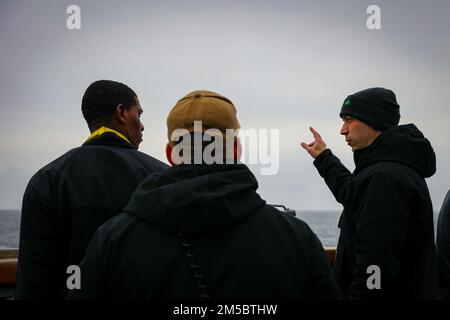 220222-N-EM691-1009 ATLANTIK (24. Februar 2022) Cmdr. James Diefenderfer, rechts, befehlshabender Offizier der Arleigh-Burke-Klasse-Guided-Raketenzerstörerin USS The Sullivans (DDG 68), leitet die Matrosen während der Übung Dynamic Guard 22-01, Februar 24, in einer Schießübung. Die Sullivans werden in das europäische Operationstheater entsandt und nehmen an einer Reihe von maritimen Aktivitäten zur Unterstützung der USA Teil Sechste Flotte und NATO-Verbündete. Stockfoto