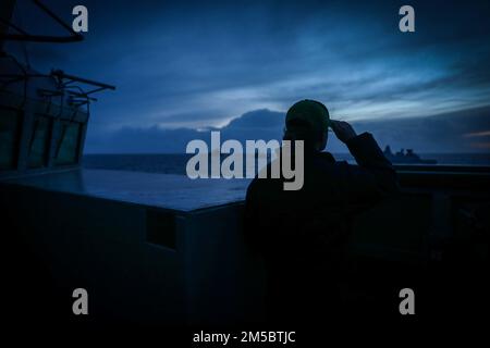 220224-N-EM691-2004 ATLANTIK (24. Februar 2022) Fähnrich Kelly Harris, der dem Arleigh-Burke-Class-Guided-Missile Destroyer USS The Sullivans (DDG 68) zugeteilt wurde, beobachtet den Abschluss der Übung Dynamic Guard 22-01 mit der ständigen NATO Maritime Group (SNMG) 1 vom 24. Februar. Die Sullivans werden in das europäische Operationstheater entsandt und nehmen an einer Reihe von maritimen Aktivitäten zur Unterstützung der USA Teil Sechste Flotte und NATO-Verbündete. Stockfoto