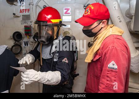 220224-N-VQ947-1045 PAZIFIK (24. Februar 2022) — Feuerwehrmann Teddralph Suan, links, aus Dededo, Guam, überprüft die Brandgrenzen mit Chief Damage Controlman James Battaglia, rechts, aus Eastlake, Ohio, während einer Hauptraummission an Bord der Amphibien-Transportanlage der San Antonio-Klasse USS Portland (LPD 27), 24. Februar 2022. Matrosen und Marines der Essex Amphibious Ready Group (ARG) und der 11. Marine Expeditionary Unit (MEU) führen derzeit Routineeinsätze in der US-3.-Flotte durch. Stockfoto