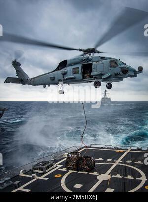 Ein an das Helicopter Maritime Strike Squadron (HSM) 48 angeschlossener Hubschrauber MH-60R Sea Hawk liefert während einer vertikalen Nachfüllung auf See mit dem Nachschuböler USNS John Lenthall (T-AO-189) während des Surface Warfare Advanced Tactical Training (SWATT) Vorräte an den Lenkraketenzerstörer USS Delbert D. Black (DGG 119). Delbert D. Black ist Teil von Destroyer Squadron (DESRON) 26, das die Carrier Strike Group (CSG) 10 unterstützt. SWATT wird vom Naval Surface and Mine Warfighting Development Center (SMWDC) geleitet und soll die Kampffähigkeit, Letalität und Intero verbessern Stockfoto