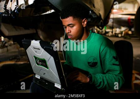 PHILIPPINE SEA (25. Februar 2022) Aviation Electrician’s Mate 3. Class Jestin Lewis aus Los Angeles verwendet ein elektronisches technisches Handbuch, um eine Hohlraumprüfung an einem EA-18G Growler durchzuführen, das den „Wizards“ des Electronic Attack Squadron (VAQ) 133 zugeteilt wurde; In der Hangarbucht an Bord des Flugzeugträgers der Nimitz-Klasse USS Abraham Lincoln (CVN 72). Die Abraham Lincoln Strike Group befindet sich in einem geplanten Einsatz im US-7.-Flottenbereich, um die Interoperabilität durch Allianzen und Partnerschaften zu verbessern und gleichzeitig als einsatzbereite Truppe zur Unterstützung einer freien und offenen Region Indo-Pacific zu fungieren. Stockfoto