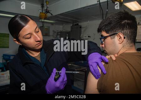PACIFIC OCEAN (25. Februar 2022) Hospital Corpsman 2. Class Angelina Mangram, aus Washington Township, N.J., dem Fleet Surgical Team (FST) 3 zugeteilt, verabreicht eine COVID-19-Impfung an Information Systems Technician 2. Class Carlos Cortez, ein Einheimischer aus Chicago, Illinois, das dem Amphibienschiff USS Essex der Wasp-Klasse zugeteilt ist (LHD 2), an Bord von Essex, 25. Februar 2022. Matrosen und Marines der Essex Amphibious Ready Group (ARG) und der 11. Marine Expeditionary Unit (MEU) führen derzeit Routineeinsätze in der US-3.-Flotte durch. Stockfoto
