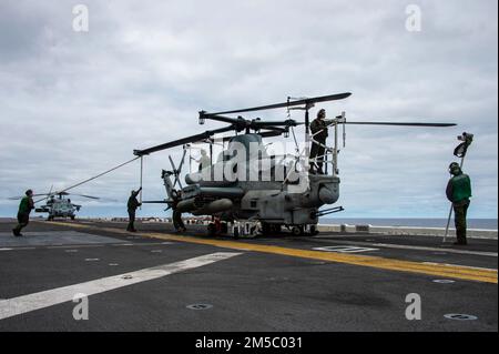 PAZIFIK (25. Februar 2022) Marines, die der 11. Marine Expeditionary Unit (MEU) zugeteilt sind, führen Wartungsarbeiten an einer AH-1Z Viper durch, die an der Marine Attack Squadron (VMM) 165 (verstärkt), 11. MEU angeschlossen ist, an Bord des Amphibienschiffs USS Essex (LHD 2) der Wasp-Klasse, 25. Februar 2022. Matrosen und Marines der Essex Amphibious Ready Group (ARG) und der 11. MEU führen derzeit Routineeinsätze in der US-3.-Flotte durch. Stockfoto