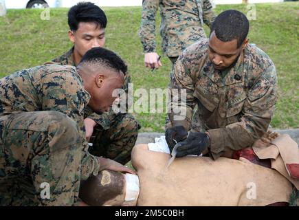 USA Navy-Matrosen mit 3. medizinischem Bataillon, 3. Marine Logistics Group, wenden taktische Gefechtsverletzten an eine Schaufensterpuppe während des Corpsman Cup in Camp Foster, Okinawa, Japan, 25. Februar 2022. Der Corpsman Cup ist eine jährlich stattfindende Herausforderung, an der Marines und Matrosen teilnehmen, um Kameradschaft aufzubauen und lebensrettende Fähigkeiten zu üben. Stockfoto