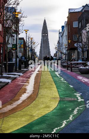 Einkaufsstraße Skolavoerdustigur, in den Farben des Regenbogens gemalt, leicht mit Schnee bedeckt, Hallgrims-Kirche hinten, Reykjavik Stockfoto