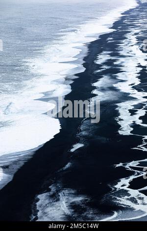 Schäumende weiße Wellen und eisige Oberflächen am schwarzen Kieselstrand Skogarsandur, in der Nähe von Dyrholaey, Sudurland, Island Stockfoto