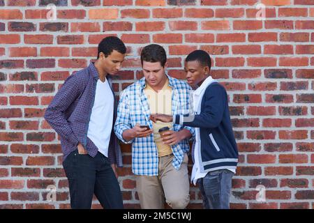 Neuigkeiten zu sozialen Medien. Eine Gruppe von Studenten, die zwischen den Klassen abhängen. Stockfoto