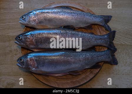 Drei frisch gefangene Forellen (Salmo trutta) auf einem Holzbrett, Bayern, Deutschland Stockfoto