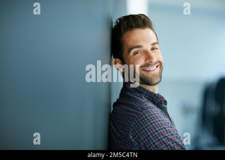Er ist so ein Charmeur. Porträt eines selbstbewussten jungen Mannes, der sich an eine Tafel lehnt. Stockfoto