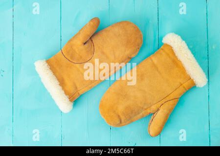 Fäustlinge aus Wildleder auf blauen Holzbrettern, Nahaufnahme mit weichem Fokus Stockfoto