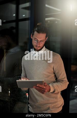 Schauen Sie nicht auf die Zeit, sondern erledigen Sie einfach Ihre Arbeit. Ein attraktiver junger Designer, der spät im Büro arbeitet. Stockfoto