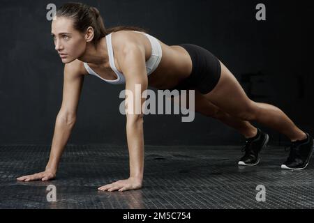 Sportlich motiviert. Studioaufnahme einer attraktiven jungen Frau, die vor einem dunklen Hintergrund trainiert. Stockfoto