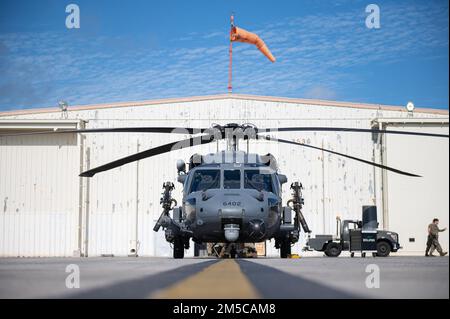 Ein HH-60G Pave Hawk, der der 33. Rettungsschwadron zugeteilt wurde, sitzt zur Wartung während einer 18. Wing Bereitschaftsübung am Kadena-Luftwaffenstützpunkt, Japan, am 1. März 2022 vor einem Hangar. Bei dieser Routineübung soll die Fähigkeit der Basis bewertet werden, ihre operative Mission zu erfüllen und die Stabilität und Sicherheit eines freien und offenen Indo-Pazifik zu gewährleisten. Stockfoto