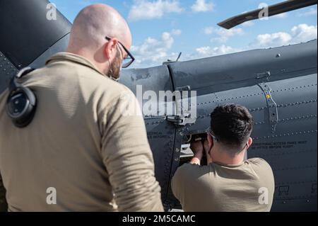 Senior Airman Joshua May, Left, beobachtet Airman 1. Class Ricky Vega, beide 33. Helicopter Maintenance Unit Crewefs führen Wartungsarbeiten an einem HH-60G Pave Hawk während einer 18. Wing Bereitschaftsübung am Kadena Air Base, Japan, am 1. März 2022 durch. Die 33. Rettungsschwadron bietet Such- und Rettungskapazitäten für Kampfhandlungen, um bei Übungen und realen Operationen in den USA zu helfen Verantwortungsgebiet des Kommandos Indo-Pazifik. Stockfoto