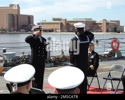 Der neu in Auftrag gegebene Chief Warrant Officer 2 Chris Harold salutiert OS2 Dondrayas Harris im Rahmen seiner Inbetriebnahmezeremonie an Bord des Schlachtschiff Wisconsin. Beide sind der USS John C. Stennis (CVN-74) zugewiesen. Die Zeremonie wurde vom Hampton Roads Naval Museum ausgerichtet, das sich neben dem Schlachtschiff in Downtown Norfolk, Virginia, befindet. Stockfoto