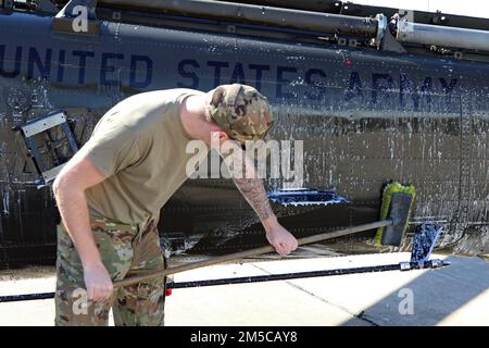 Nebraska Army National Guard Spc. Dylan DeBoer, ein Hubschrauber-Mechaniker, der der Golf Company (MEDEVAC) zugewiesen wurde 2-104. General Support Aviation Bataillon, wäscht einen UH-60 Black Hawk in der Army Aviation Support Facility #1 in Lincoln, Nebr., 1. März 2022. Stockfoto