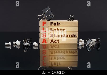 Geschäftskonzept. Auf einer schwarzen reflektierenden Oberfläche, Knöpfen, Clips und Holzblöcken mit der Aufschrift - Fair Labor Standards Act Stockfoto