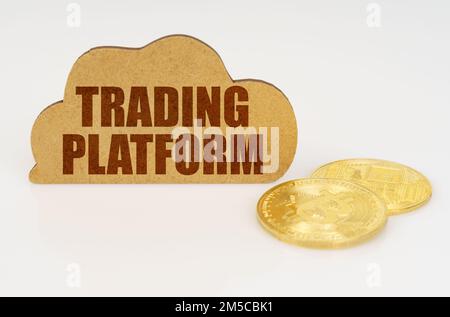 Geschäfts- und Technologiekonzept. Bitcoins liegen auf einer weißen Oberfläche und es gibt ein Schild - eine Wolke mit der Inschrift - Handelsplattform Stockfoto