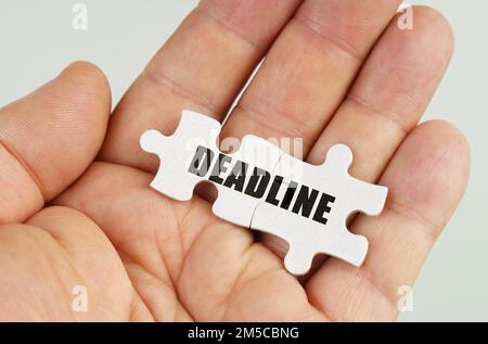 Geschäftskonzept. In der Hand eines Mannes sind Rätsel mit der Inschrift - DEADLINE Stockfoto