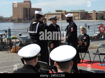 Der neu in Auftrag gegebene Chief Warrant Officer 2 Chris Harold salutiert OS2 Dondrayas Harris im Rahmen seiner Inbetriebnahmezeremonie an Bord des Schlachtschiff Wisconsin. Beide sind der USS John C. Stennis (CVN-74) zugewiesen. Die Zeremonie wurde vom Hampton Roads Naval Museum ausgerichtet, das sich neben dem Schlachtschiff in Downtown Norfolk, Virginia, befindet. Stockfoto