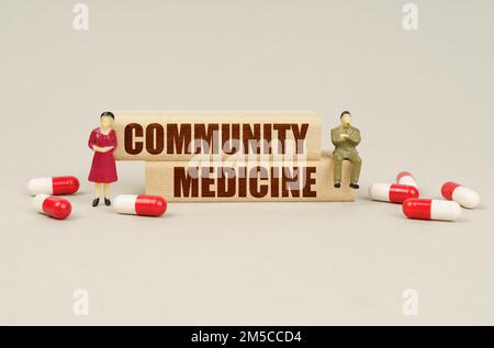 Medizinisches Konzept. Neben den Miniaturfiguren der Menschen befinden sich Tafel und Holzblöcke mit der Inschrift "Community Medicine" Stockfoto