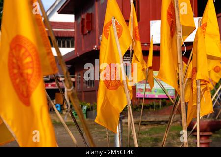 Nahaufnahme der gelben buddhistischen Flaggen (die Dharmacakra-Flagge) vor dem Phan Tao-Tempel in Chiang Mai, Thailand. Stockfoto