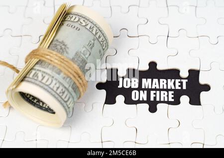 Geschäftskonzept. Dollar liegen auf weißen Rätseln, auf einer schwarzen Oberfläche ist eine Inschrift - Job Market ist in Flammen Stockfoto
