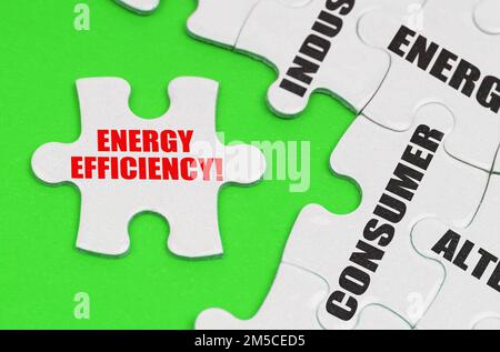 Energiekonzept. Auf einer grünen Oberfläche befinden sich weiße Puzzles mit Inschriften, auf einem separaten Puzzle befindet sich eine Inschrift - Energieeffizienz Stockfoto